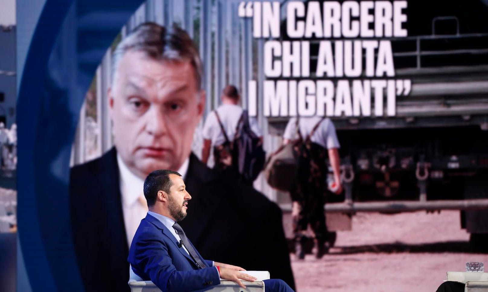Italiens Innenminister Matteo Salvini in einer italienischen Talkshow, im Hintergrund ein Foto von Ungarns Premier Viktor Orban.