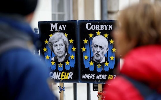 Wollen gemeinsam nach einer Lösung suchen: Premierministerin Theresa May und der Chef der oppositionellen Labour-Partei, Jeremy Corbyn, auf Protesttafeln.