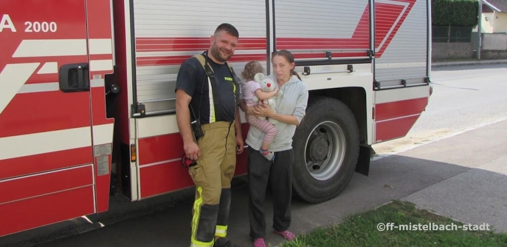 Die erleichterte Mama und die Kleine mit ihrem Teddy gemeinsam mit dem Retter.