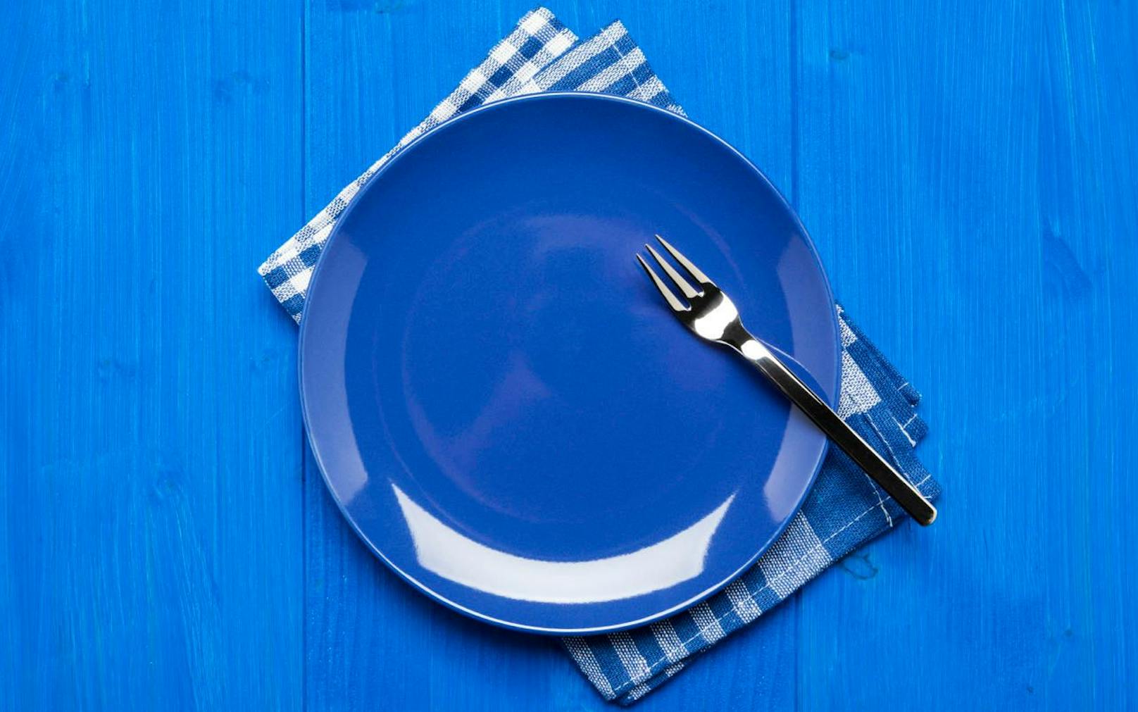 Blue plate with fork on napkin and blue table