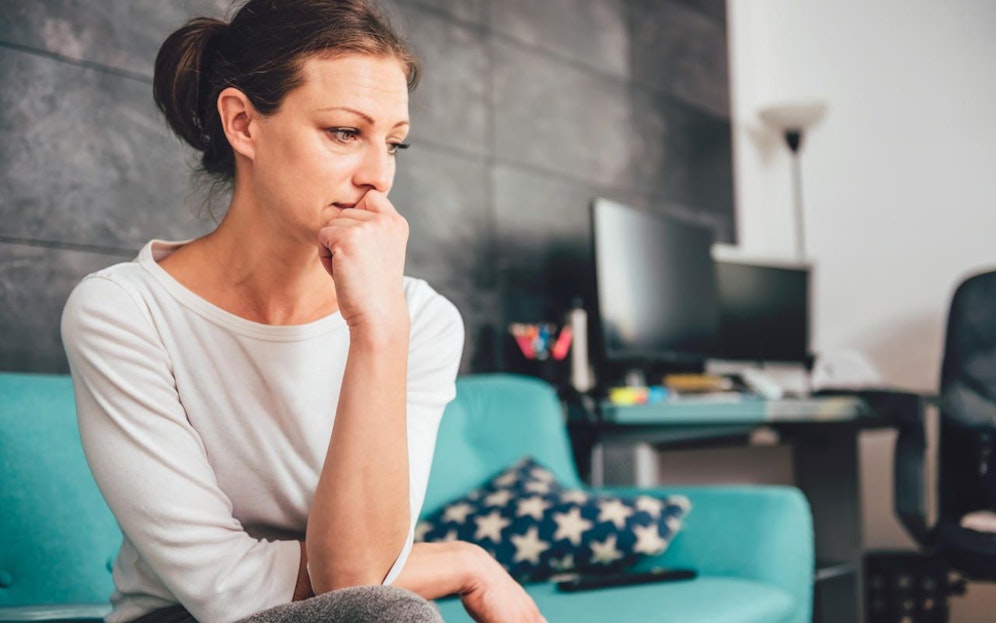 Sad woman sitting on a sofa in the living room