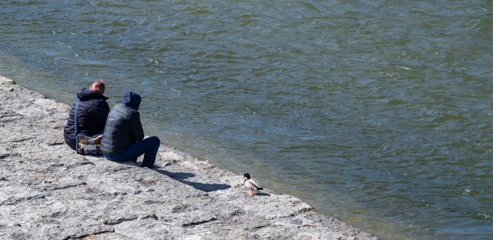 Zwei Menschen sitzen an der Isar in der bayrischen Landeshauptstadt München.
