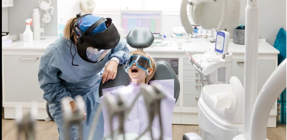 Tina Merhaut führt bei einer kleinen Patientin die Mundhygiene mit Schutzschild durch. 