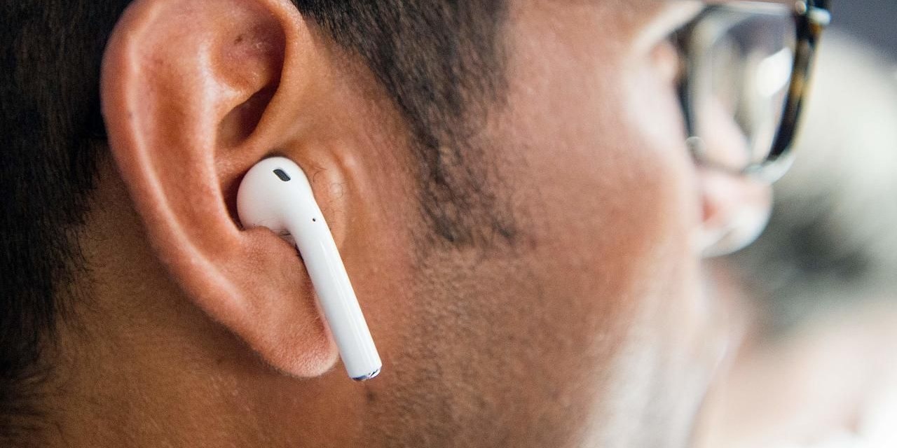 Apple Airpod im Ohr eines Mannes. Symbolfoto.