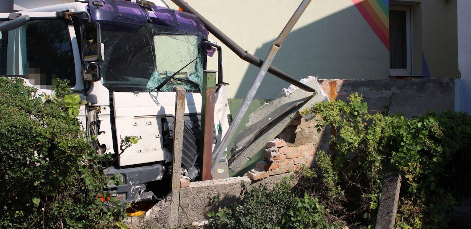 Lkw krachte nach der Kollision mit einem Pkw in eine betonierte Gartenmauer.