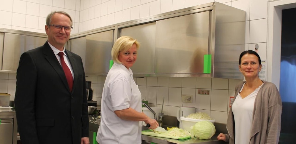 Vizebürgermeister Michael Paternostro (li.) und Kindergartenleiterin Alexandra Bauer (re.) schauen in die Töpfe von Köchin Maria Lindner (Mi.).