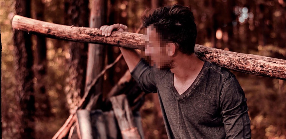 Ein junger Mann mit einem geschulterten Baumstamm. Symbolfoto.