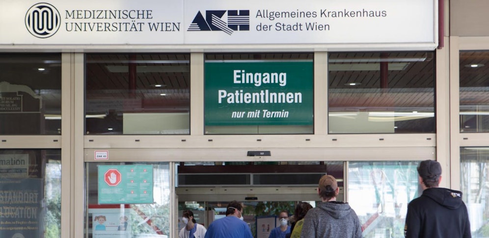 Personen vor einem Absperrband vor dem Patieneingang des Allgemeinen Krankehaus (AKH) in Wien.
