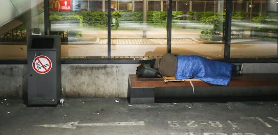 Ein Obdachloser schläft auf einer Bank am Bahnhof von München.