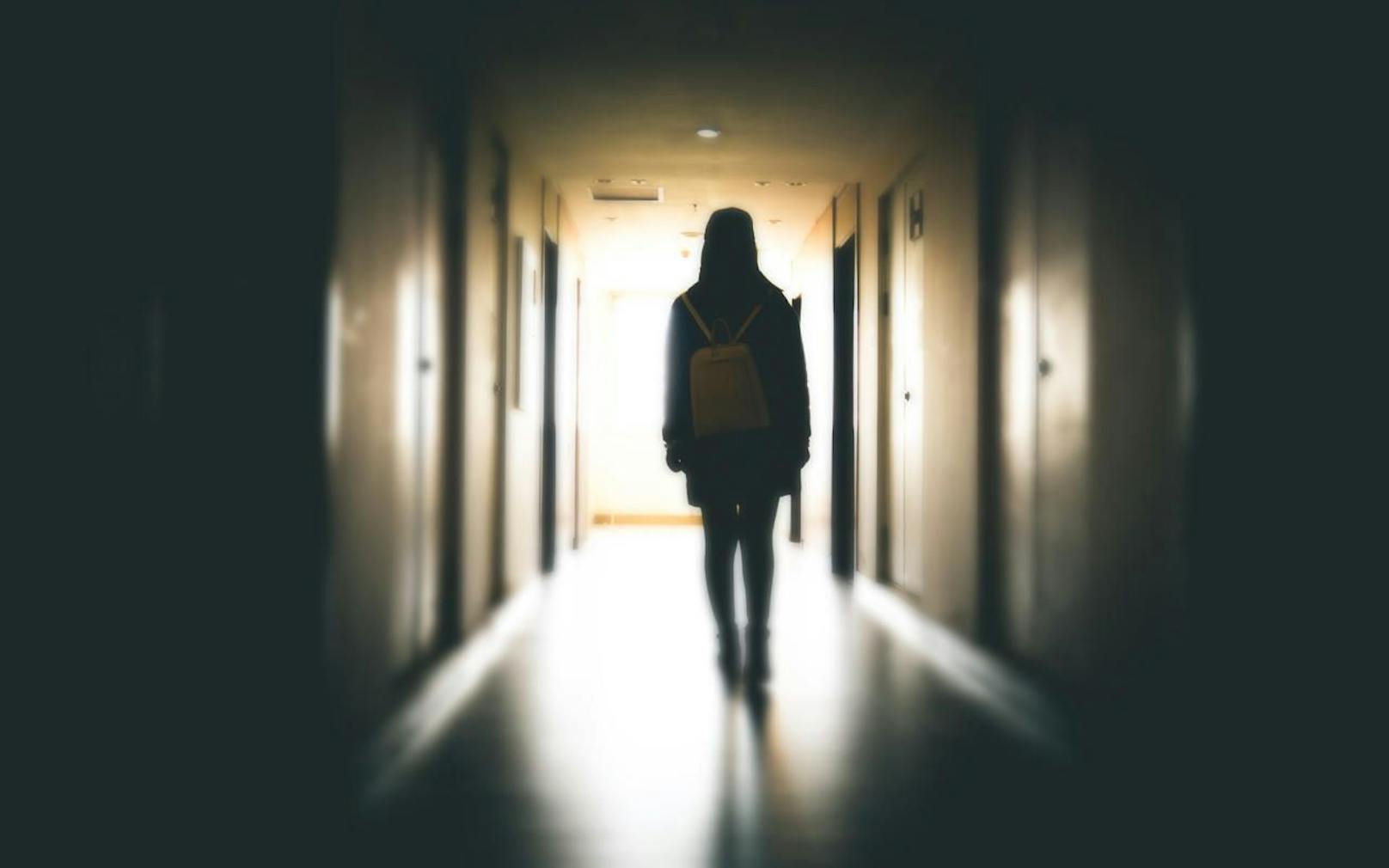 Eine junge Frau alleine in einem dunklen Gebäude. Symbolbild