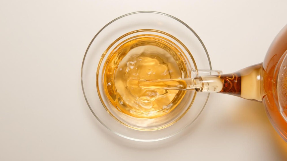 TOP VIEW: Fresh tea flowing to a tea cup from a teapot