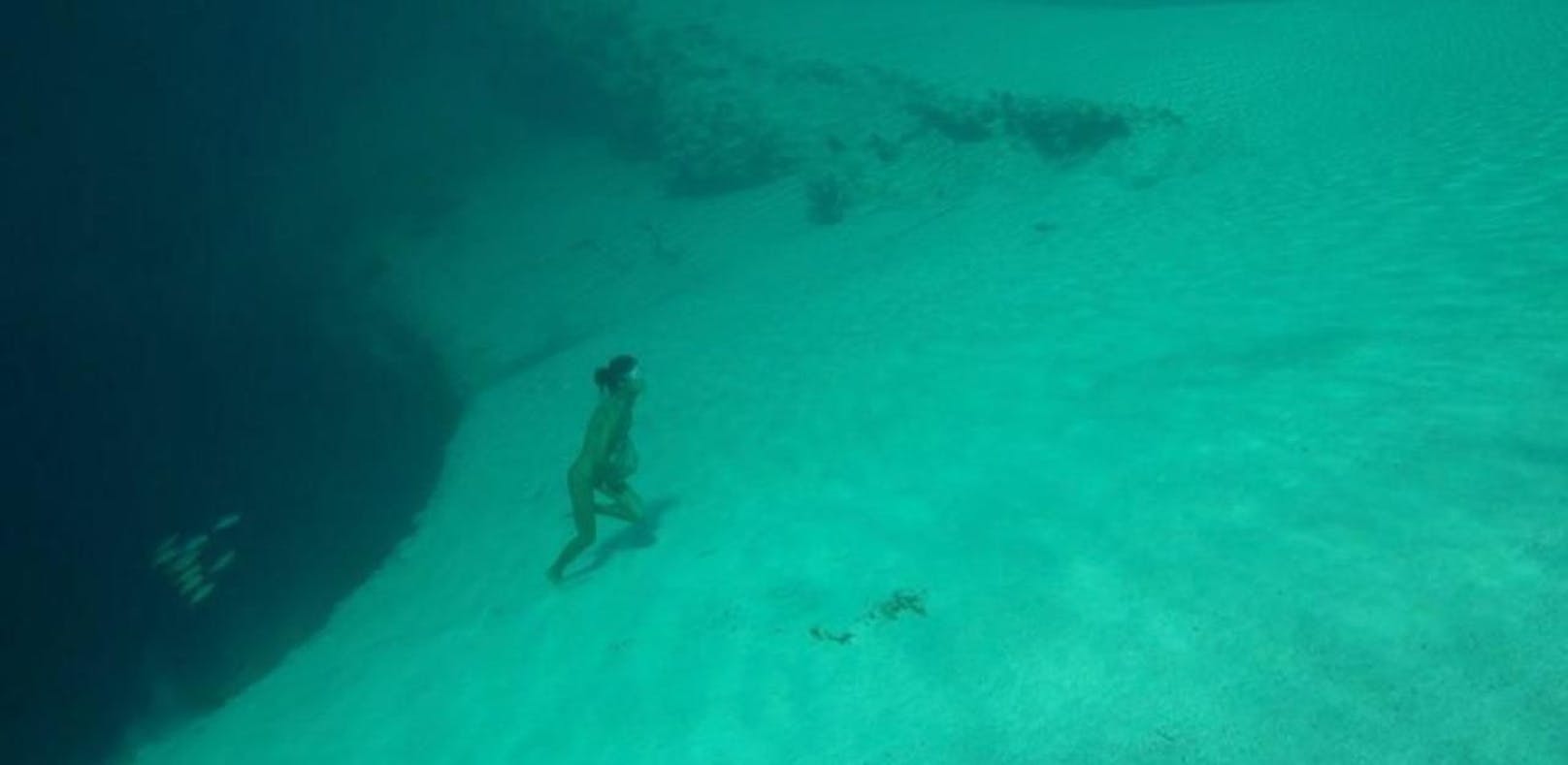 Taucherin klettert unter Wasser auf einen Abhang