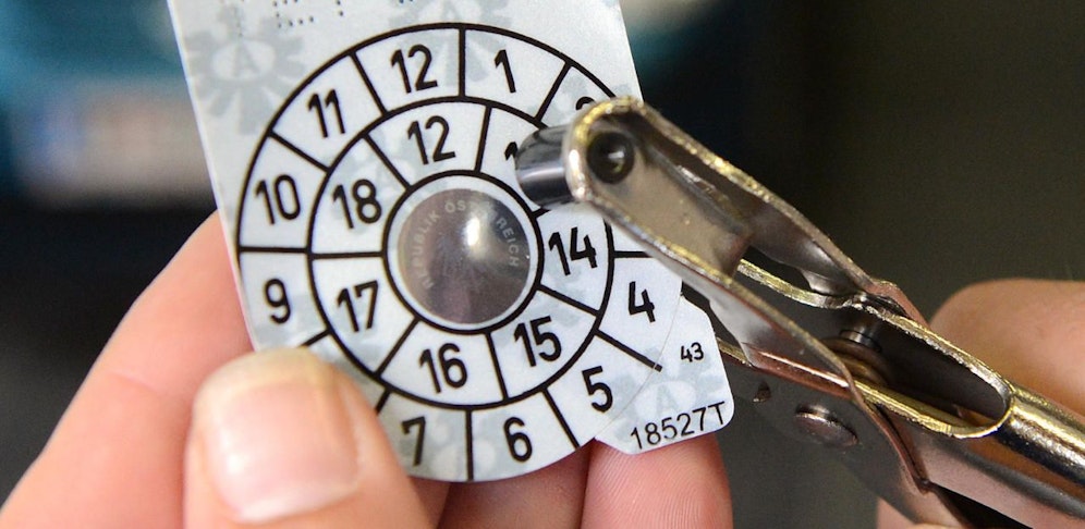 Ein Mechaniker locht eine Begutachtungsplakette für Kraftfahrzeuge, umgangssprachlich auch "Pickerl" genannt. Symbolbild