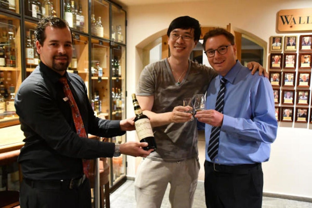 Prost: Der Gast aus China (Bildmitte) und Hotelier Sandro Bernasconi (rechts). Der Macallan-Sammler aus Asien hat sich soeben in einem Schweizer Hotel ein Glas Whisky für 8.700 Euro gegönnt.