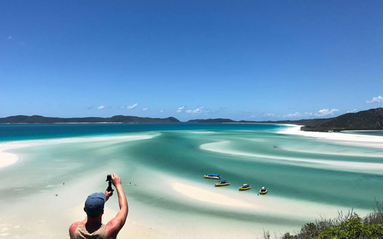 Ein Tourist macht ein Foto am Whitehaven Beach auf den Whitsunday Islands. Diese sind Teil des Great Barrier Reef im Osten Australiens.
