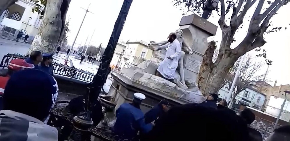 Mehrere Sicherheitsmänner versuchen den Mann vom Brunnen zu bekommen.