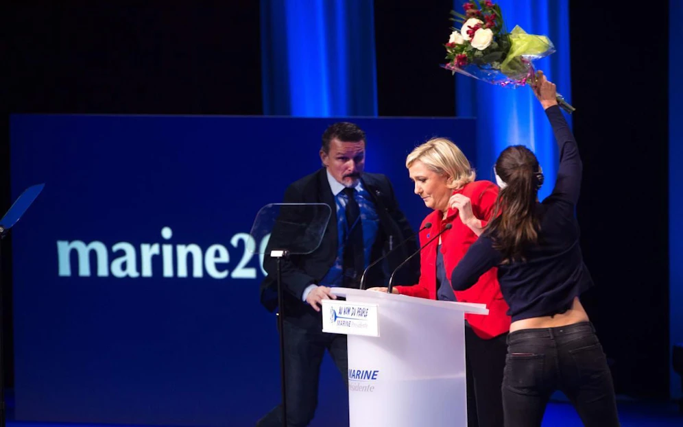 Eine Femen-Aktivistin attackiert mit einem Blumenstrauß Marine Le Pen. Credit: Pricturedesk)