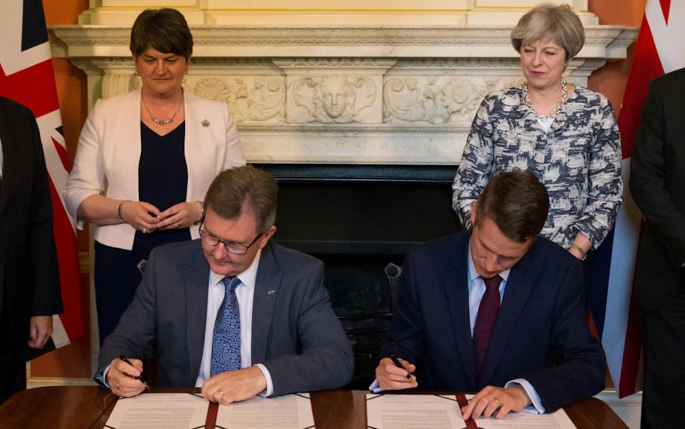 Mit Argusaugen überwachen Arlene Foster (l.) und Theresa May (r.) die Unterzeichnung der gegenseitigen Vereinbarung.
