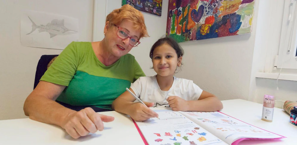 Brigitte (60) hilft Basima (9) bei der Hausübung. 