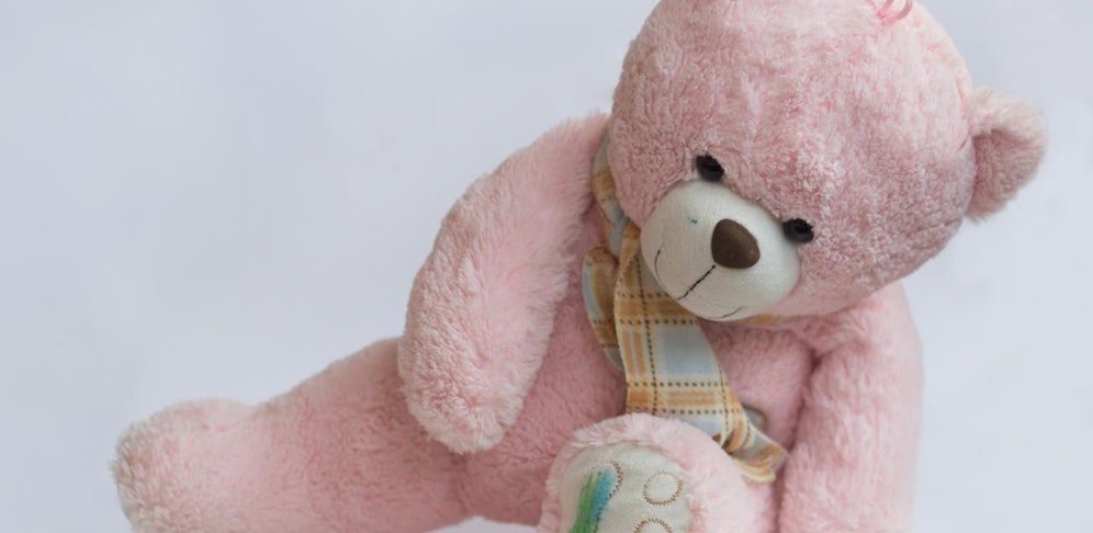 Rosa Teddybär mit farbigen Pfoten und Gesicht. Symbolfoto