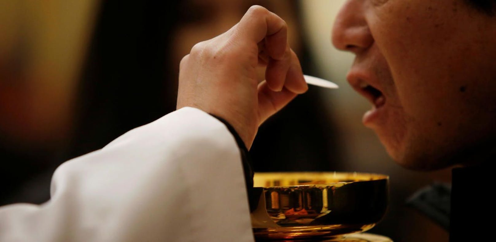 Ein Gläubiger empfängt die Mundkommunion während einer katholischen Messe in Beijing.