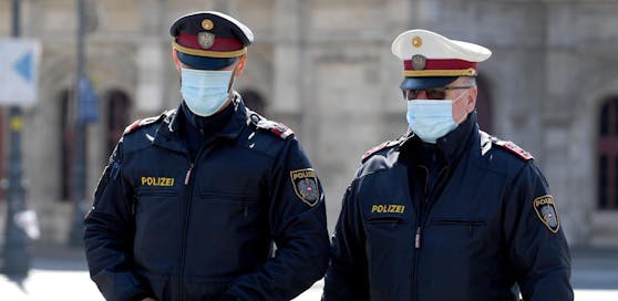 Polizisten mit Mund- und Nasenschutz kontrollieren die Einhaltung der Coronavirus-Maßnahmen.