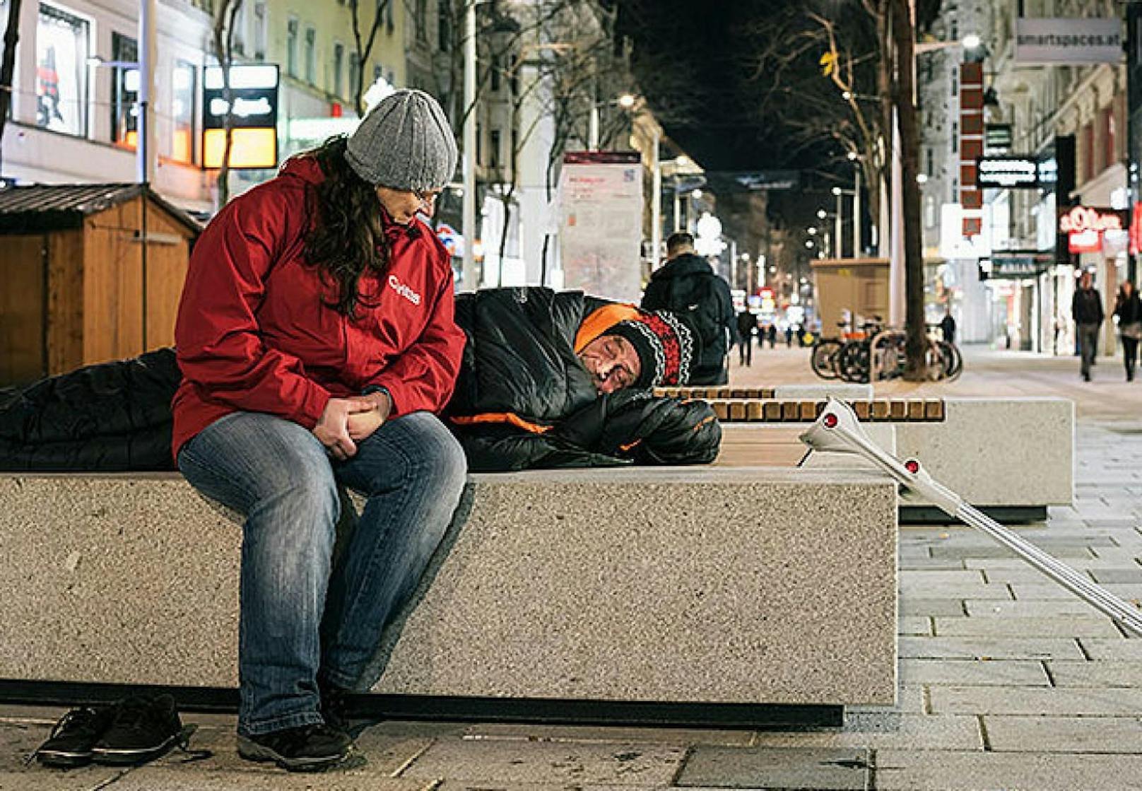 Caritas-Mitarbeiterin kümmert sich um Obdachlosen, der auf der Mariahilfer Straße schläft.