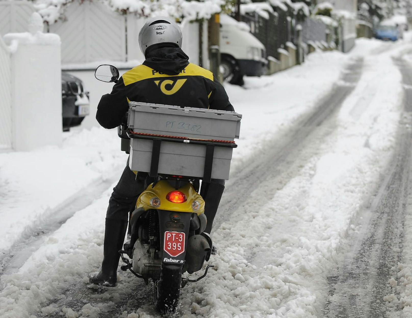 Ein Briefträger der Österreichischen Post AG mit dem Motorroller auf rutschiger Schneefahrbahn. Archivbild: 29.
November 2010, Wien.