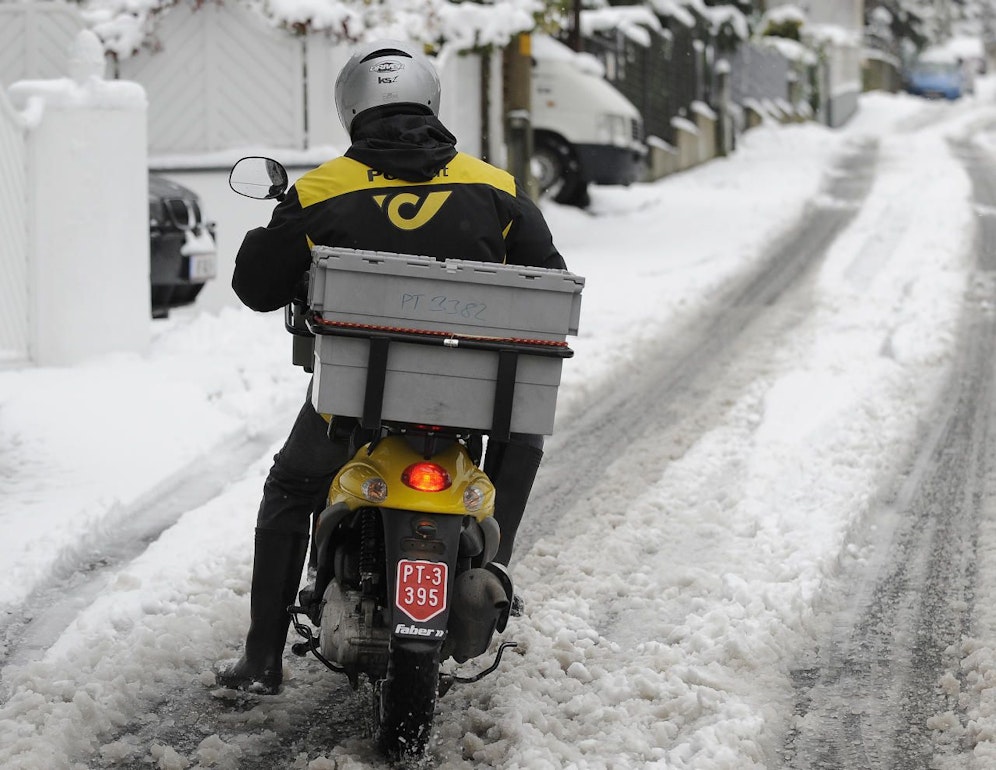 Ein Briefträger der Österreichischen Post AG mit dem Motorroller auf rutschiger Schneefahrbahn. Archivbild: 29. November 2010, Wien.