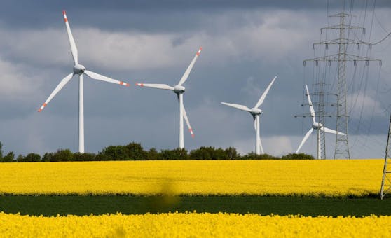 Eine Hochspannungsleitung und Windkrafträder vor einem Rapsfeld. Aufgenommen am 3. Mai 2019.