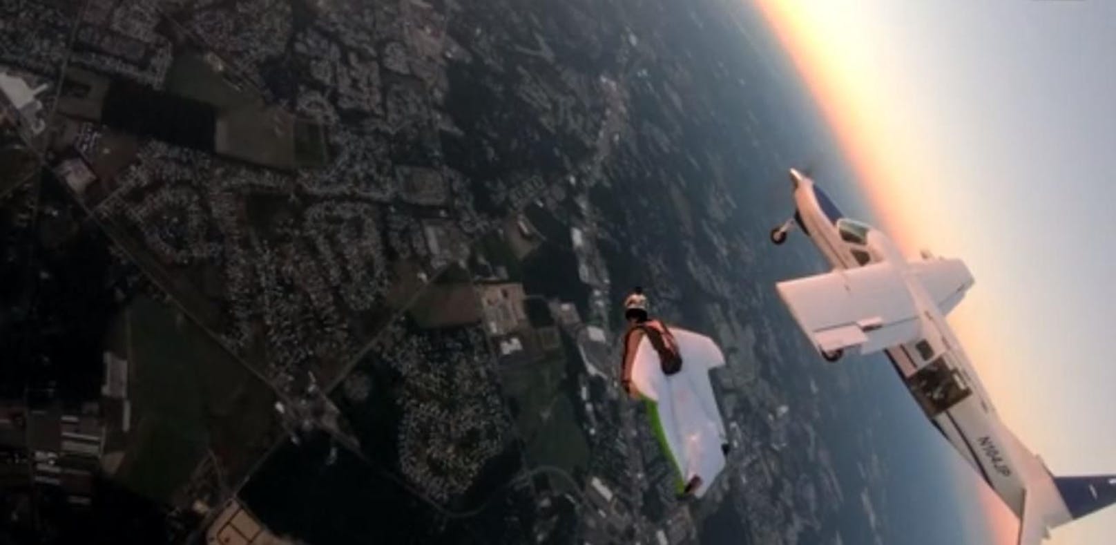 Fallschirmspringerin fliegt neben Flugzeug