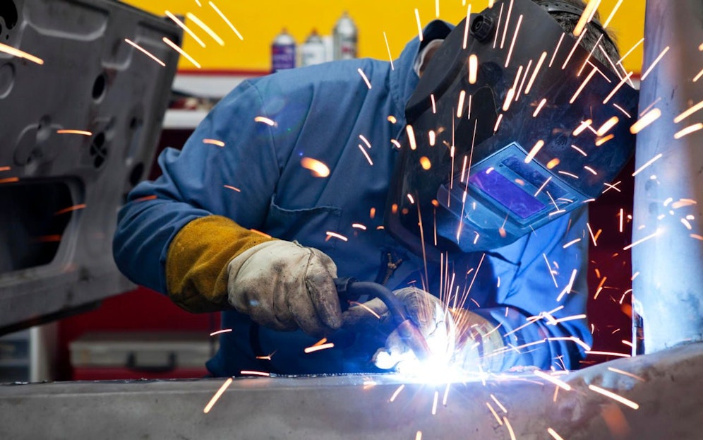 Ein Automechaniker führt Schweißarbeiten an einer Fahrzeugkarosserie durch. Symbolfoto.