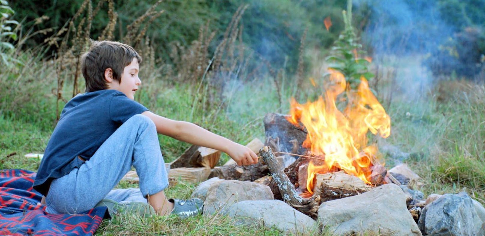 Ein Kind an einem Lagerfeuer. Symbolbild
