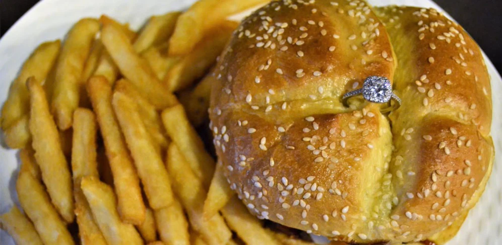 Der Verlobungsring wird in einem Burger serviert.