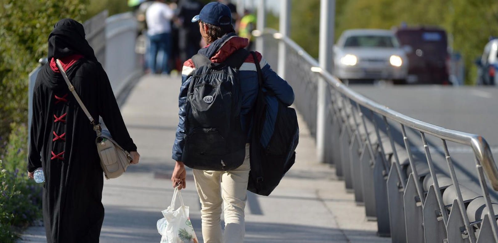 Flüchtlinge sind am Mittwoch, 17. September 2015, zu Fuß in kleineren Gruppen von Salzburg in Richtung Grenzübergang Freilassing unterwegs und werden von der Polizei direkt nach dem Übergang Saalbrücke angehalten und zur Registrierung gebracht.