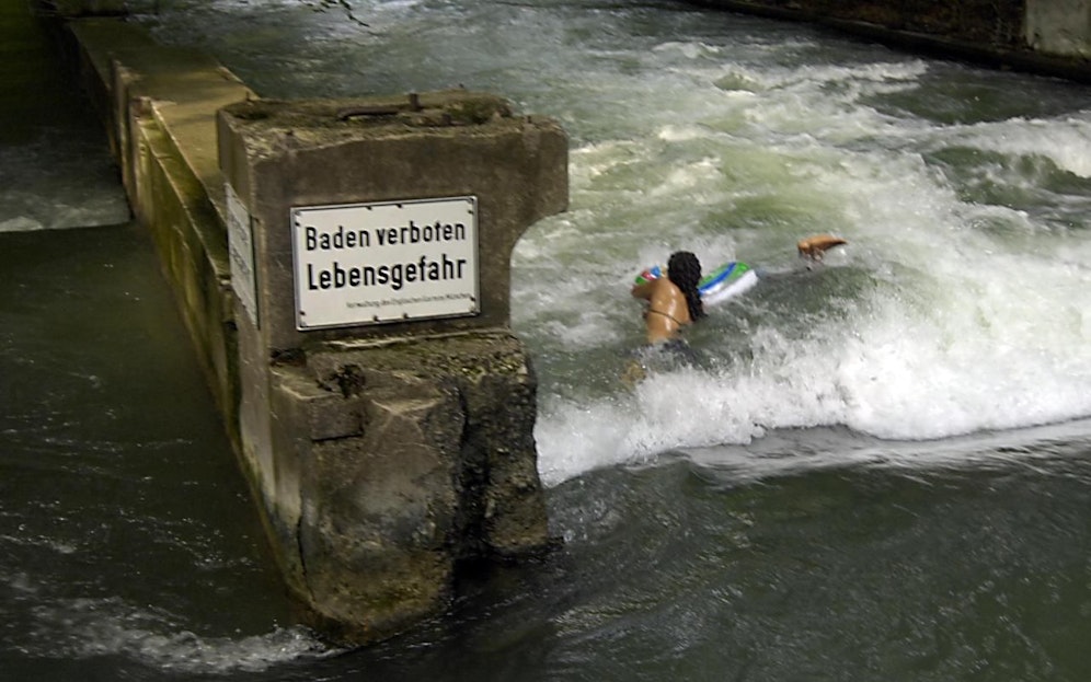 Ein Schild "Baden verboten - Lebensgefahr" warnt Schwimmer vor einer gefährlichen Wasserwalze im Münchner Eisbach. Symbolfoto
