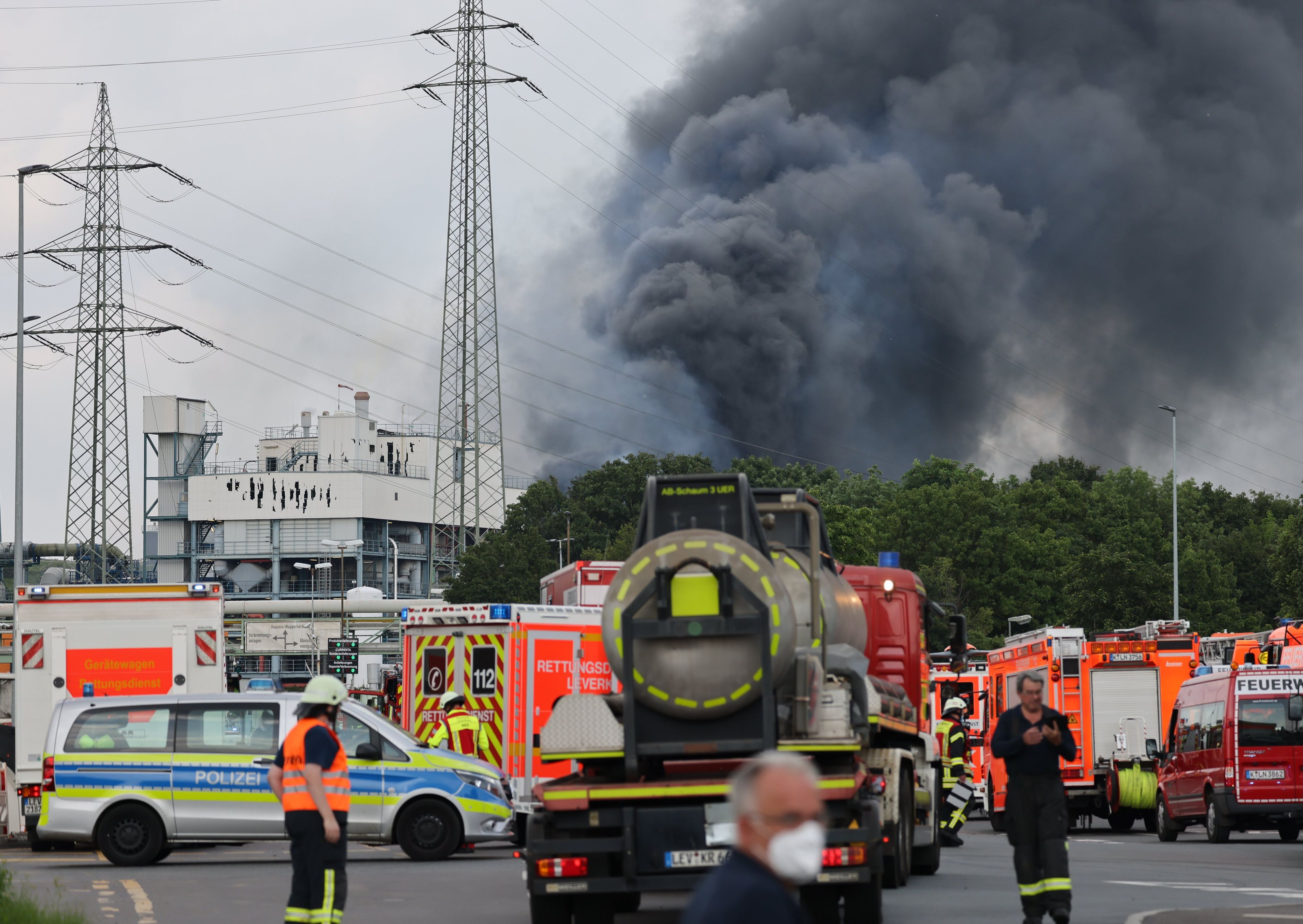 Download von www.picturedesk.com am 27.07.2021 (12:35).  27 July 2021, North Rhine-Westphalia, Leverkusen: Emergency vehicles of the fire brigade, rescue services and police stand not far from an access road to the Chempark over which a dark cloud of smoke is rising. After an explosion, fire brigade, rescue services and police are currently in large-scale operation, the police explained. Due to the damage, the busy motorway A1 near Leverkusen has been closed. Photo: Oliver Berg/dpa - 20210727_PD15980 - Rechteinfo: Rights Managed (RM)