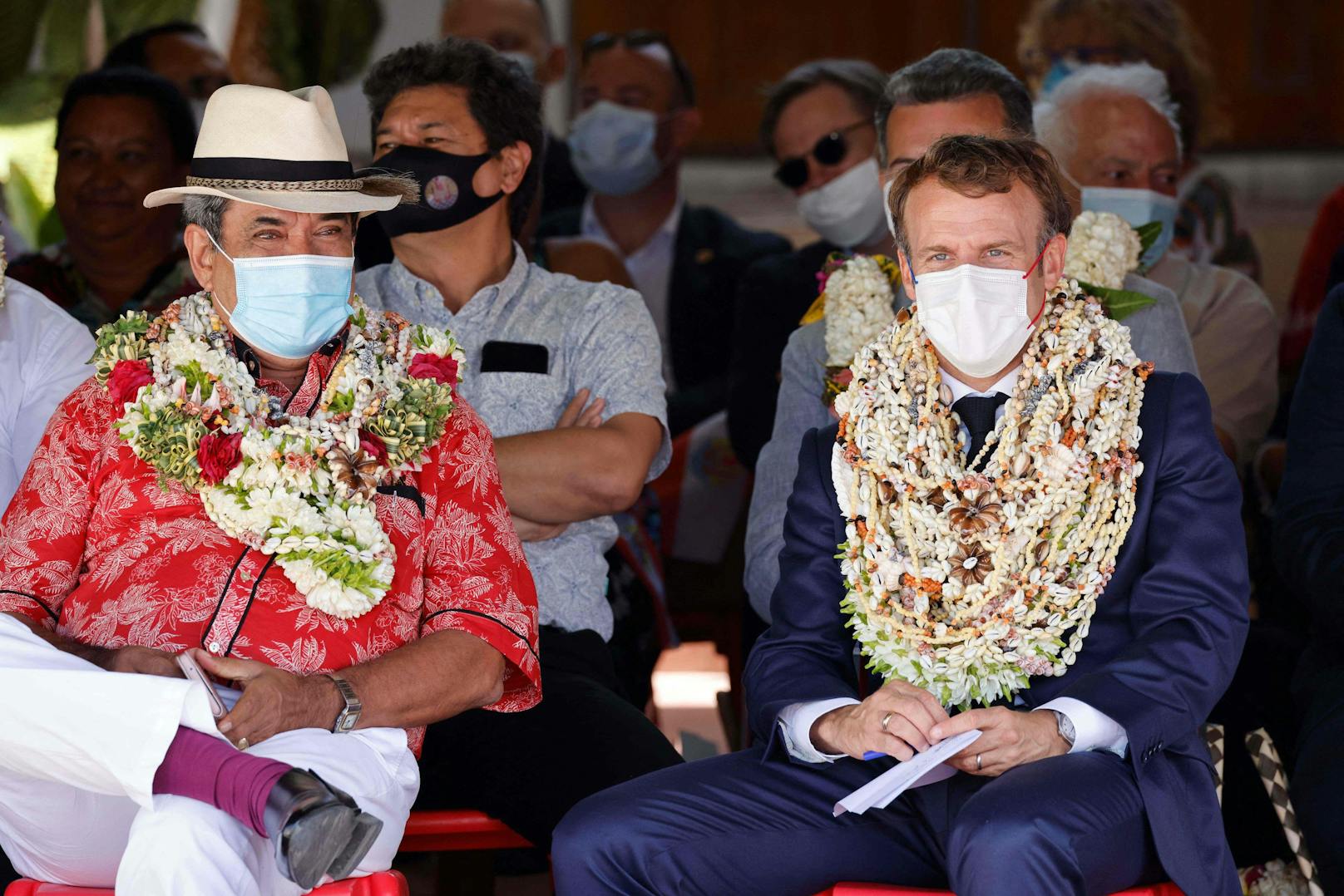 Emmanuel Macron wurden als Willkommensgeste Blumenkränze umgehängt.