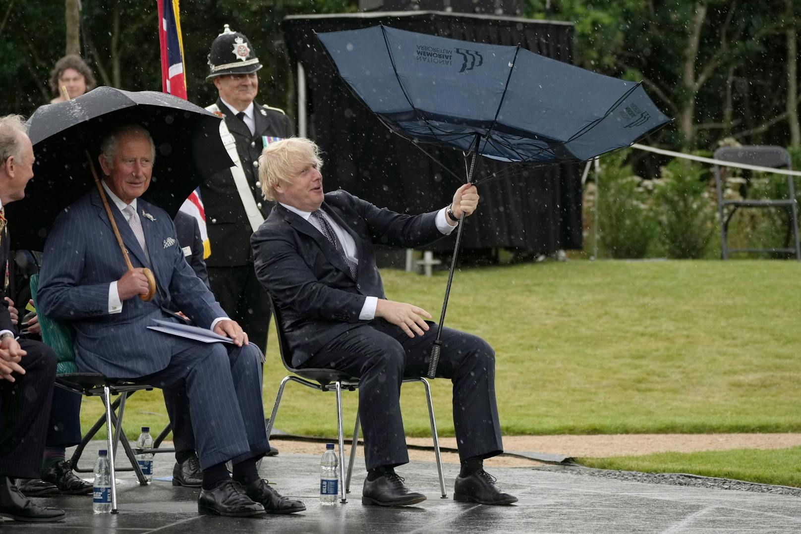 Johnson kämpfte mit dem Schirm. Auch der Polizist hinter ihm musste, wie Charles, schmunzeln.