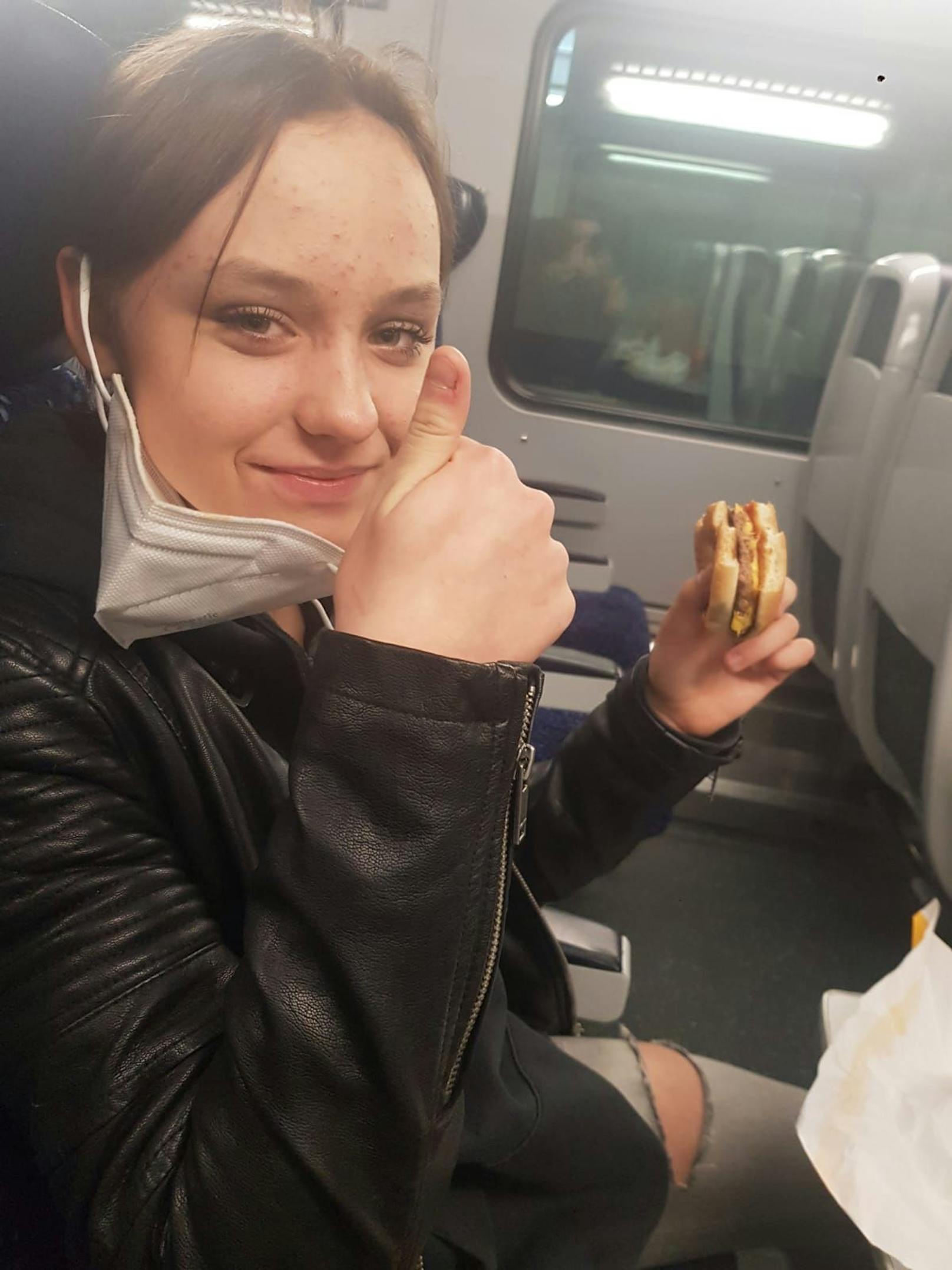 Leonie mit Burger und gut gelaunt im Zug.