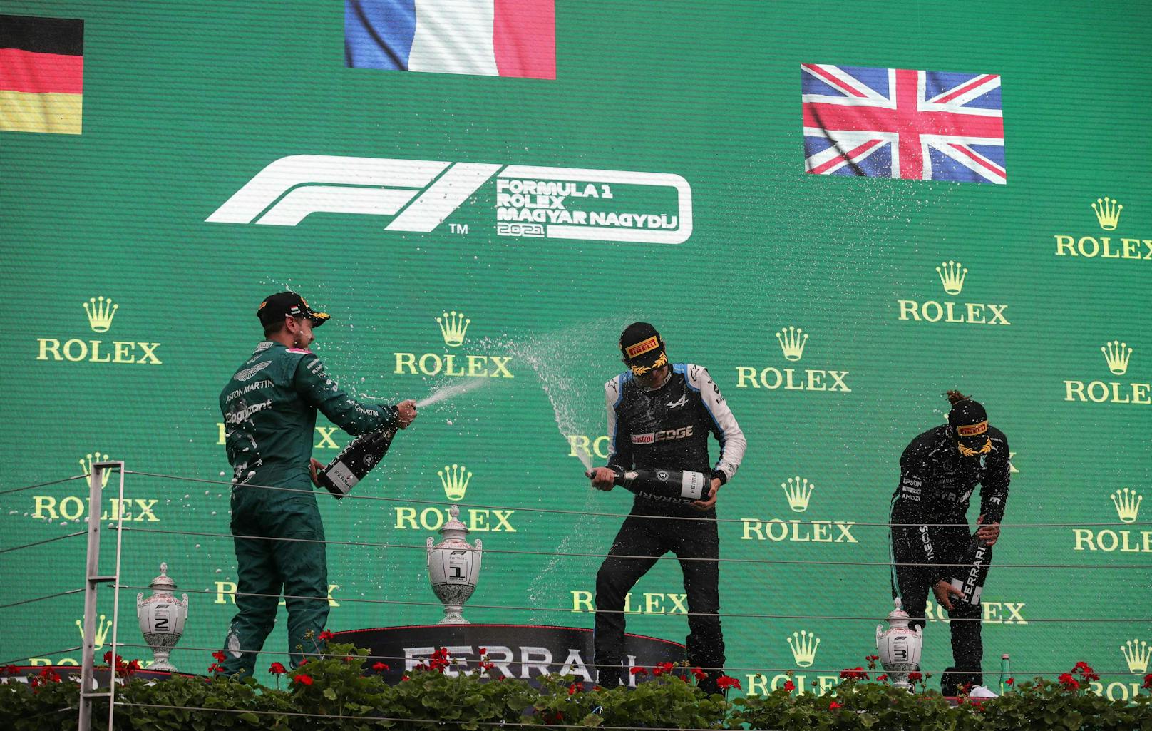 Sieger Esteban Ocon und Sebastian Vettel feiern mit der Champagner-Dusche, Lewis Hamilton kämpft sichtlich mit Kreislaufproblemen.