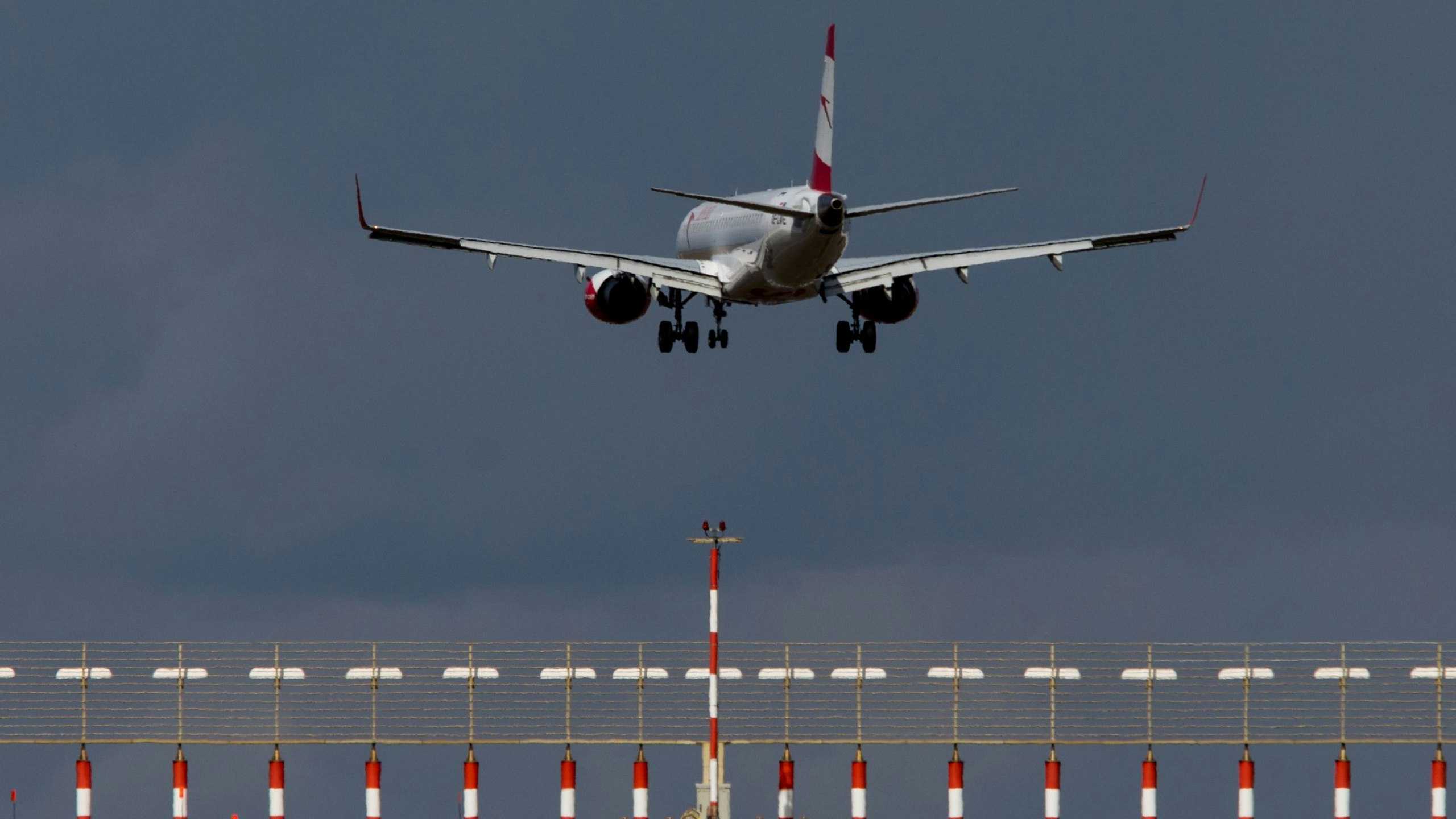 Eine Bombardier Embraer 195 der Austrian Airlines während des Landeanflugs auf die Piste 34 über der Pistenbefeuerung am 11. März 2019 bei Sturm und dunklen Wolken am Vienna International Airport (VIE, LOWW).
