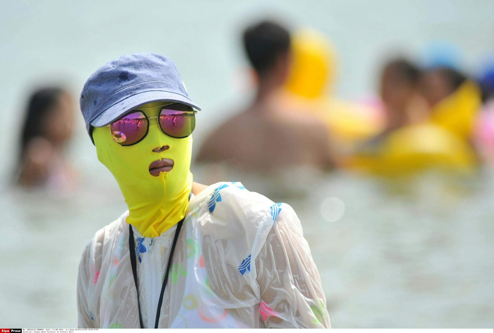 Strandbesucherin mit Facekini als Sonnenschutz in Qingdao / China.