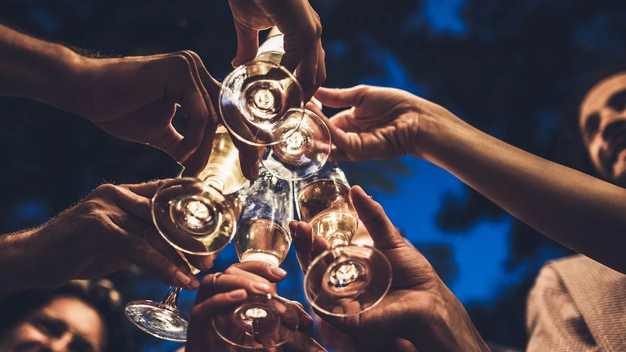 Close up of group of unrecognizable people toasting with champagne on a night party.