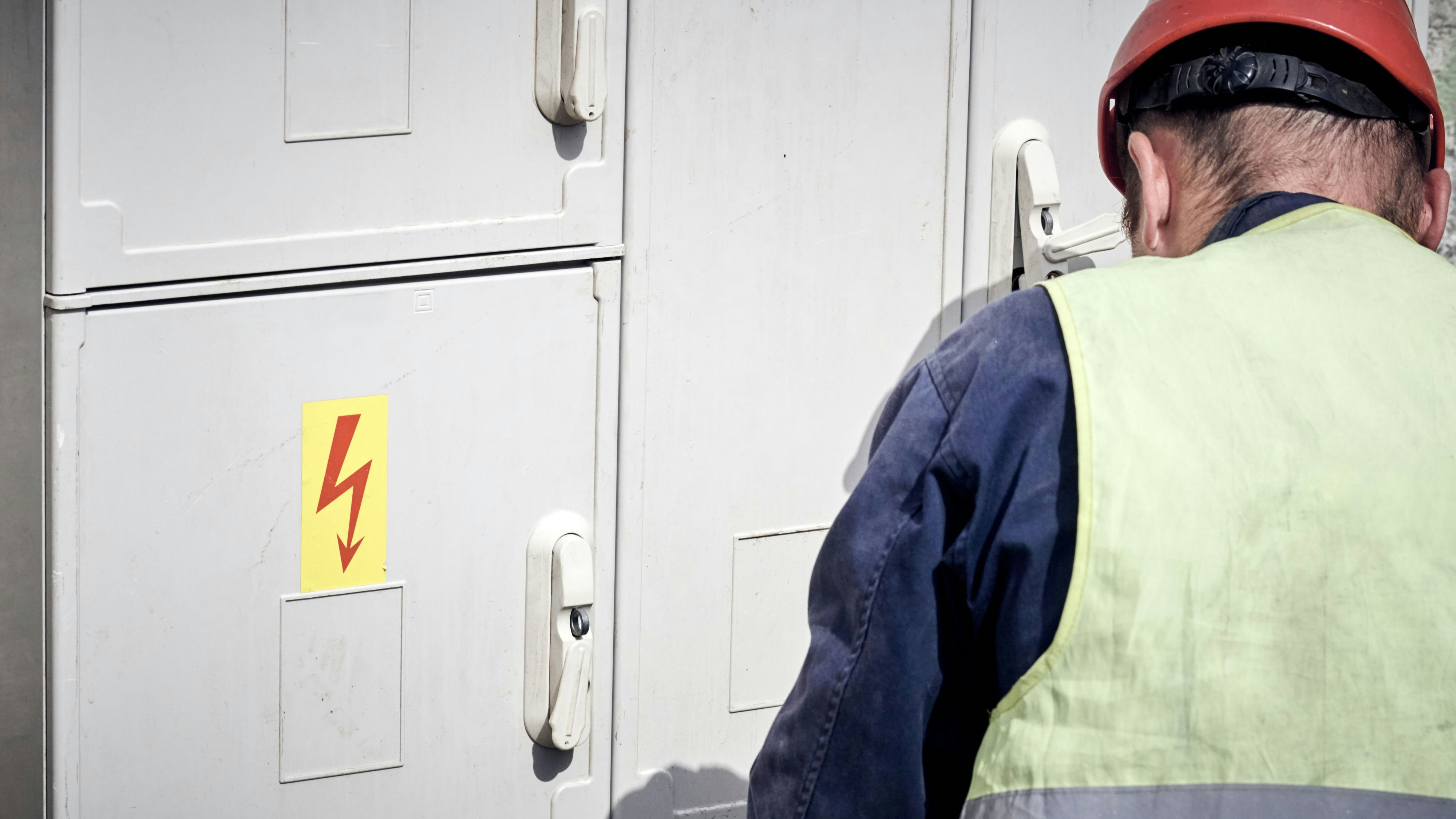 Electrician maintaining fuse box with high voltage components.