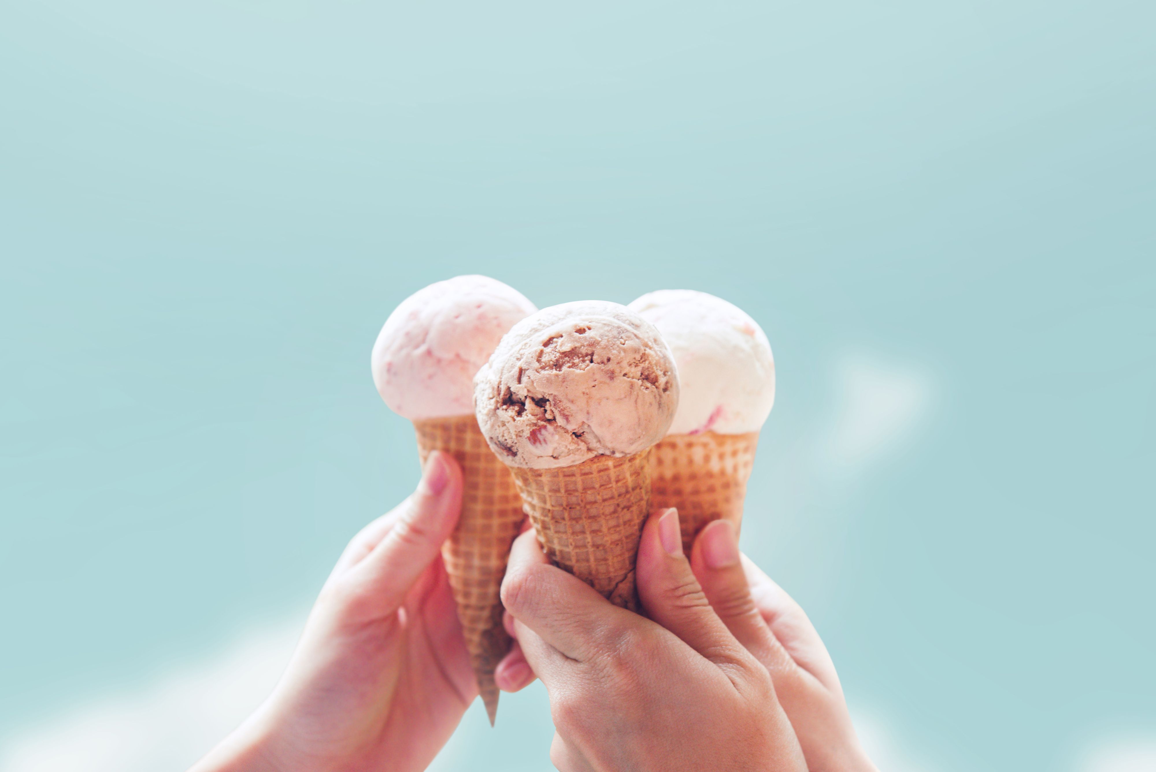 Young woman hands holding ice cream cones on sky summer background