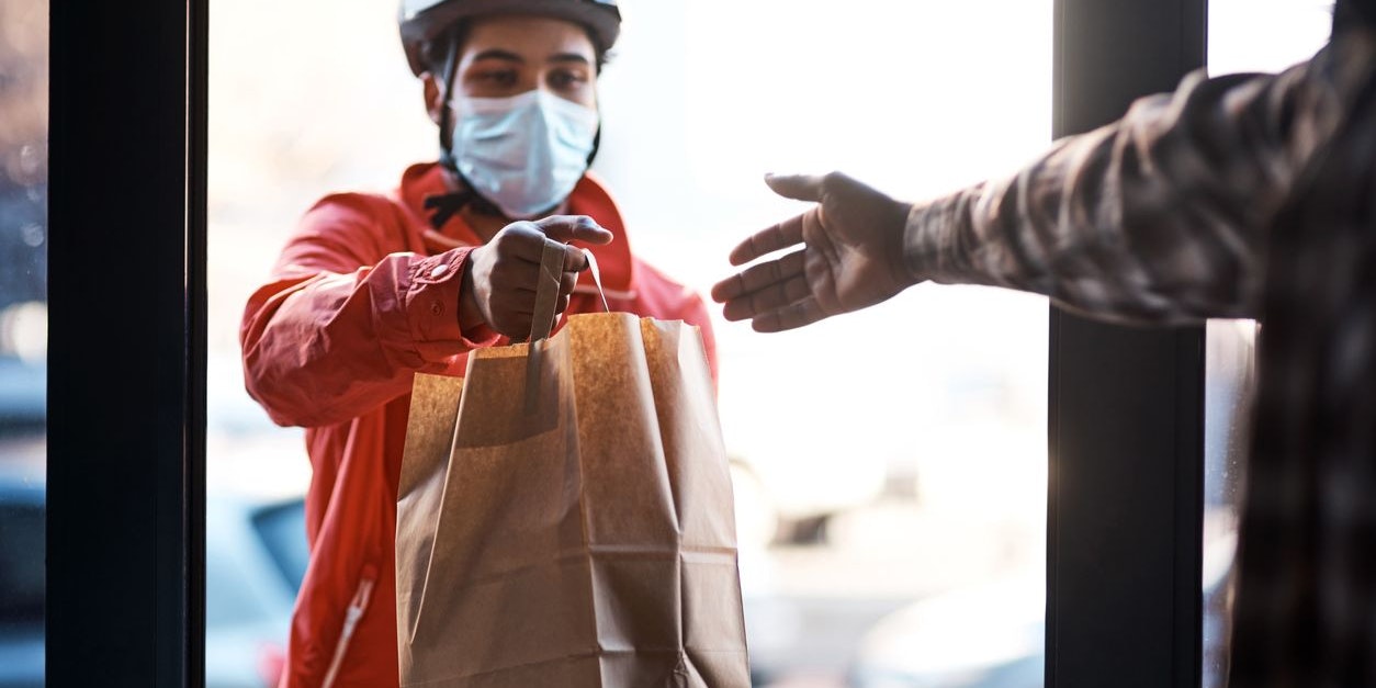 Shot of a masked man delivering a food package