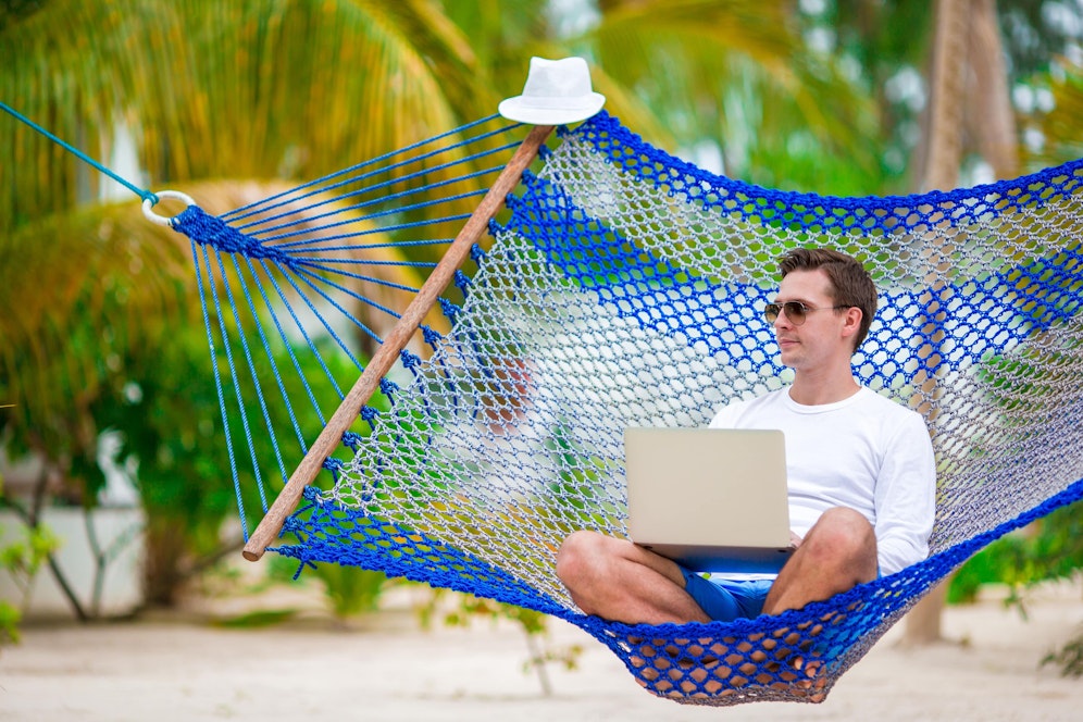 Symbolfoto eines Urlaubers mit Laptop im Gepäck.