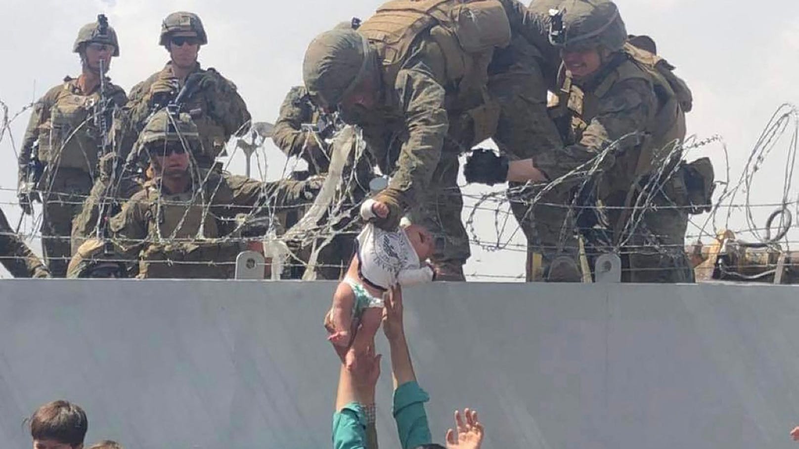 Verzweifelt reichte ein Vater sein Baby über einen Stacheldraht an US-Soldaten weiter.