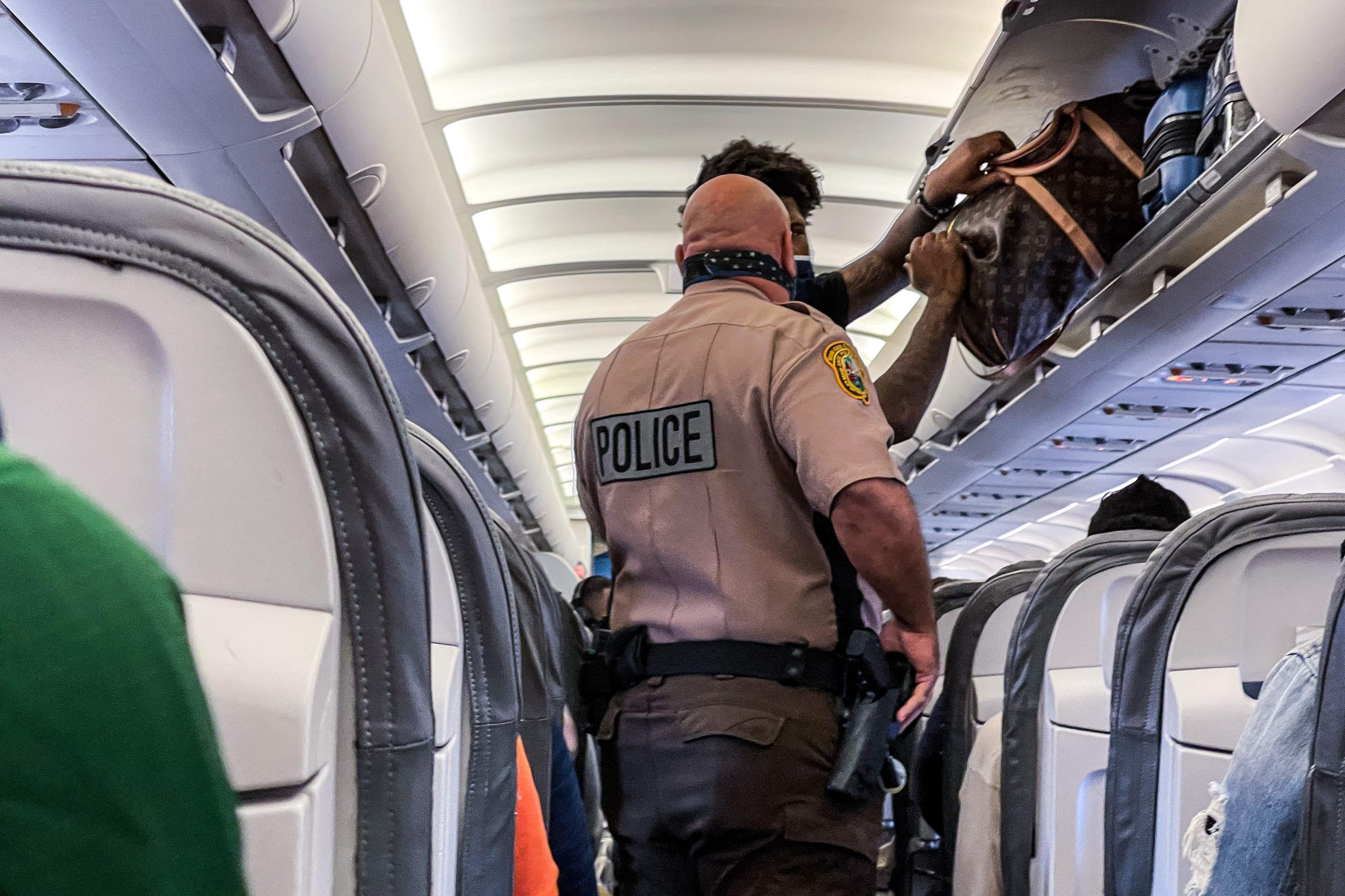Download von www.picturedesk.com am 23.08.2021 (12:37).  An officer from the Airport District Police of Miami International Airport removes passenger Dontavious Jackson from a United Airlines flight in Miami, on March 17, 2021, after Jackson was accused of wrongdoing by another passenger. - Jackson was later let go based on various eye witness statements from other passengers. (Photo by CHANDAN KHANNA / AFP) - 20210317_PD11892 - Rechteinfo: Rights Managed (RM) Nur für redaktionelle Nutzung! Werbliche Nutzung erfordert Freigabe: bitte schicken Sie uns eine Anfrage.